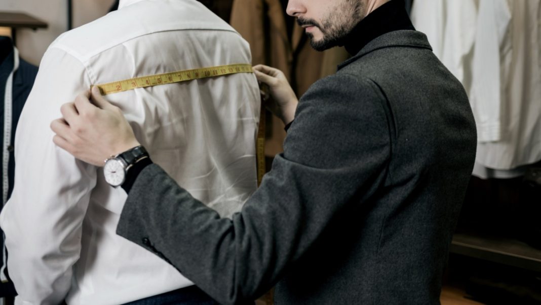 A tailor works on a mans suit, creating something bespoke