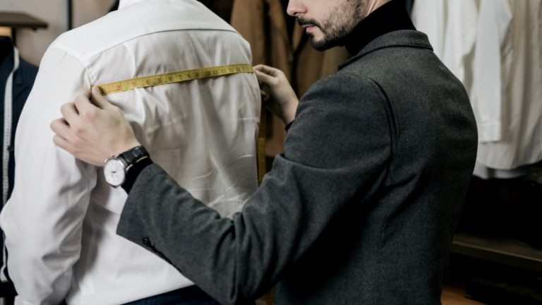 A tailor works on a mans suit, creating something bespoke