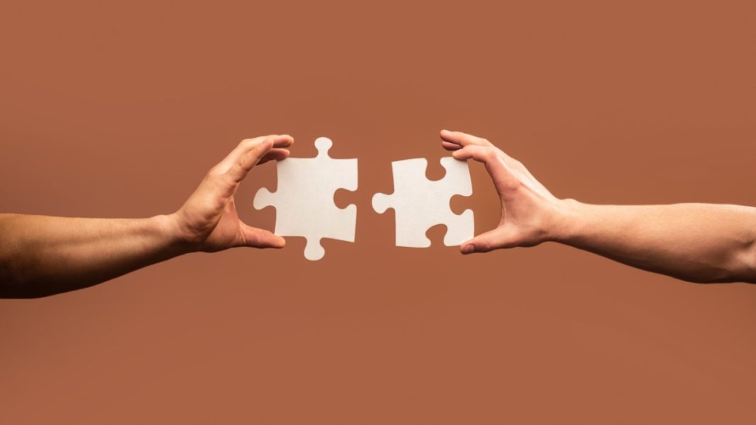 Two puzzle pieces being brought together
