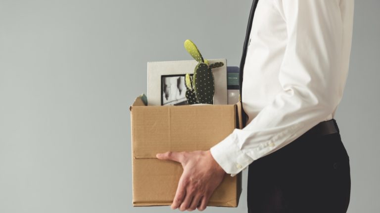 Man holds cardboard box after losing job