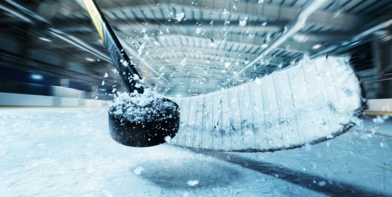 Hóquei vara batendo disco preto na superfície de gelo nevado